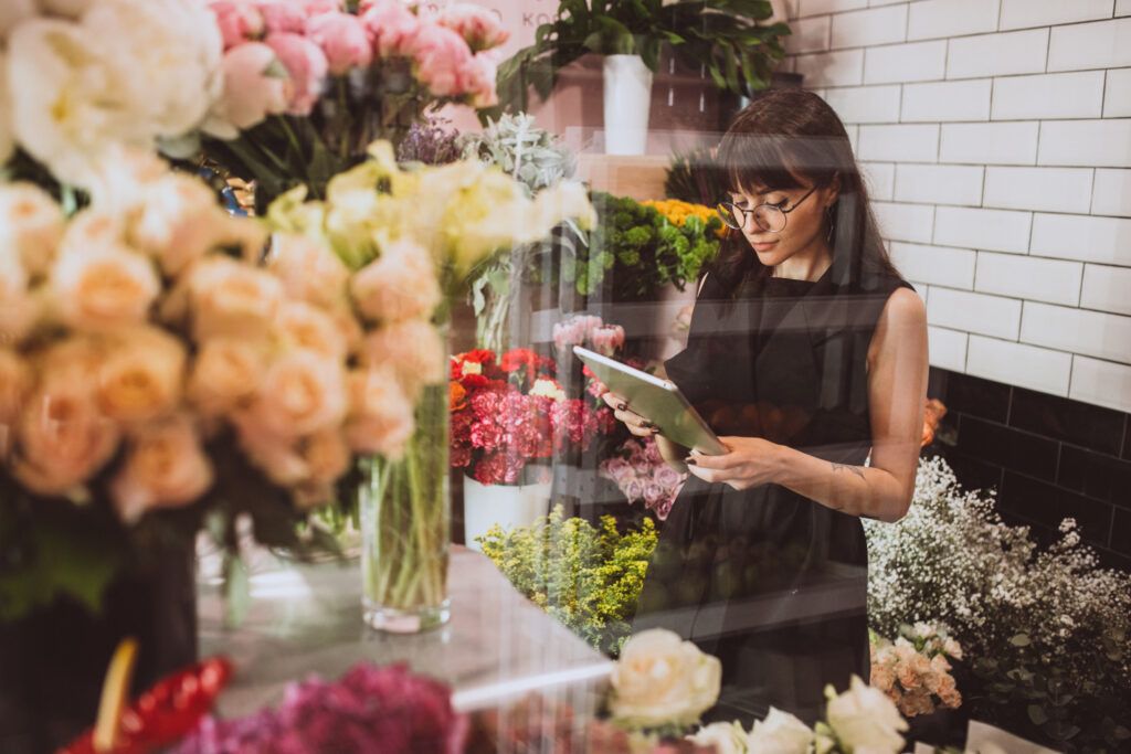 Woman florist at her own floral shop taking care of flowers