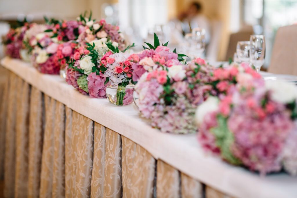 Round bouquets of pastel pink and green flowers stand on long di