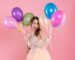 front view excited party girl with party cap holding balloons near her face