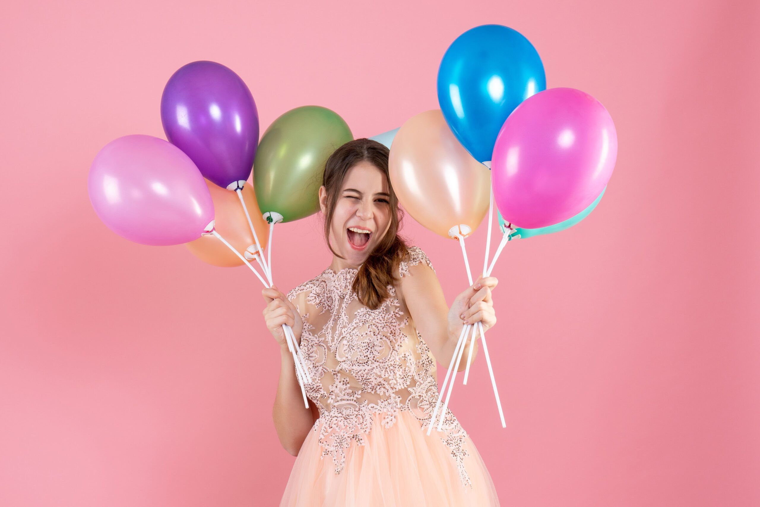 front view excited party girl with party cap holding balloons near her face